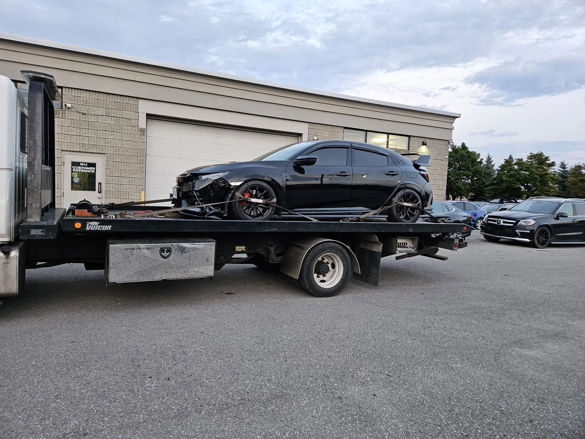 Black car being towed on a flatbed truck, scrap car removal service in North York,